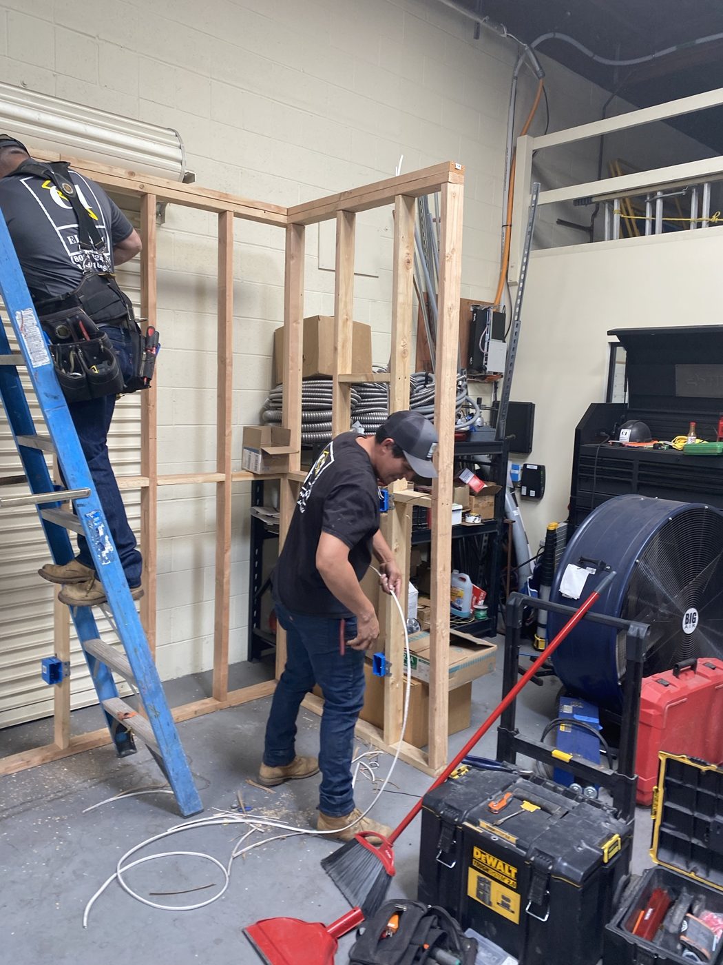 Two C1 Electric crew members wiring the shop training wall